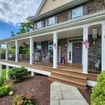 A large, two-story house with a spacious front porch featuring a 