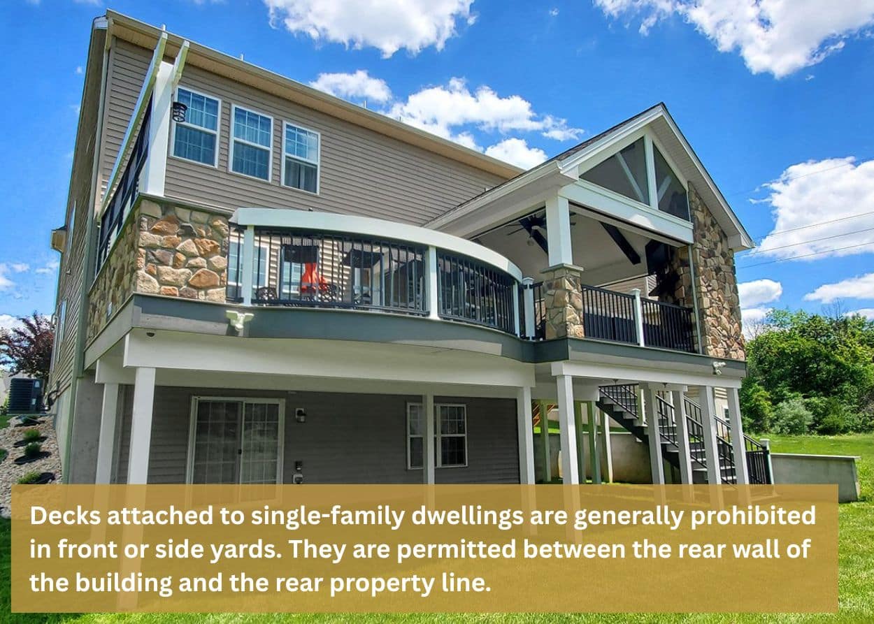 Decks attached to single-family dwellings are generally prohibited in front or side yards. They are permitted between the rear wall of the building and the rear property line.