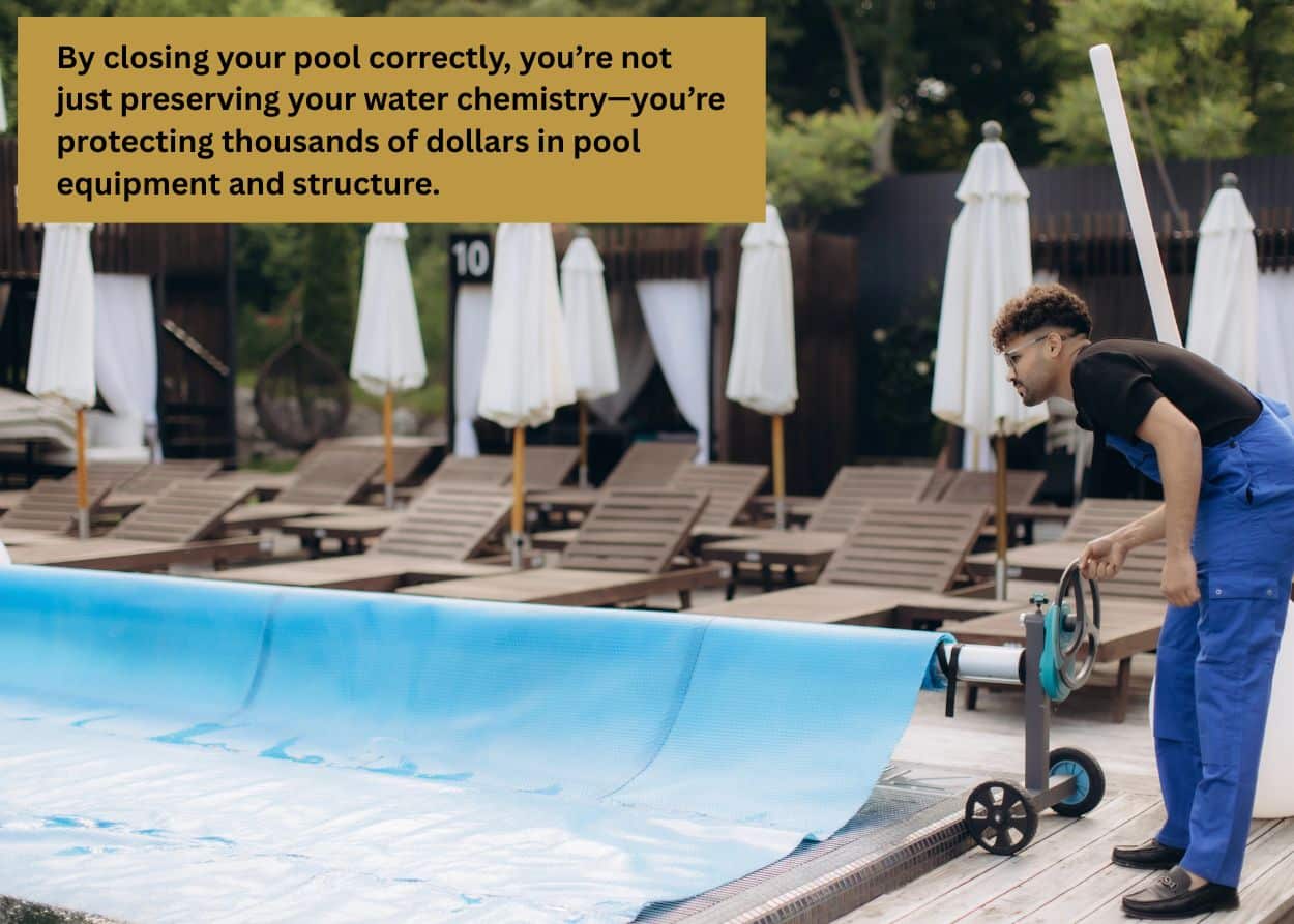 Pool maintenance worker using a reel system to roll up a blue solar pool cover beside a row of lounge chairs and umbrellas at an outdoor pool area. Caption: By closing your pool correctly, you’re not just preserving your water chemistry—you’re protecting thousands of dollars in pool equipment and structure.