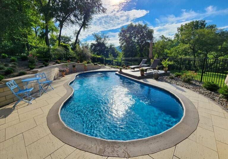 concrete pool and patio with surrounding fence