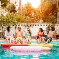 Group of happy friends relaxing in swimming pool - Young people having fun in exclusive summer tropical vacation - Friendship, holidays and youth lifestyle concept